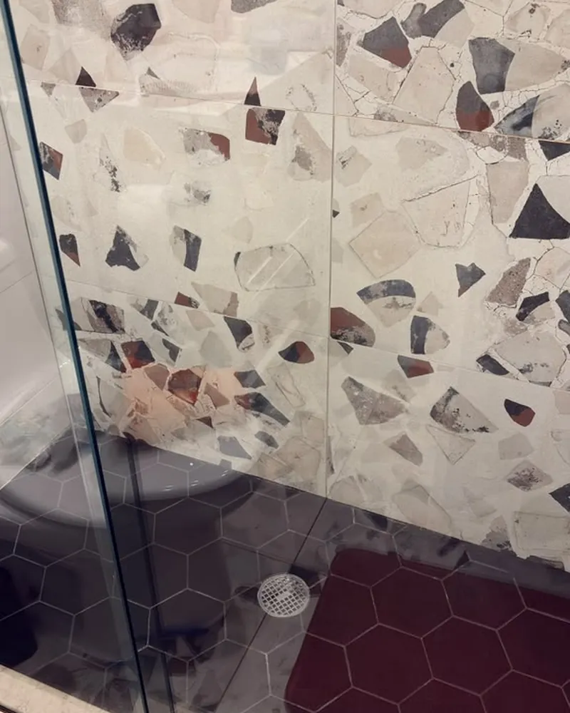 Regadera de terrazo con piso hexagonal limpio y puerta de vidrio